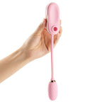 Hand holding OTOUCH LOUIS pink clitoral suction vibrator showing suction opening at top and G-spot vibrating egg hanging on cord for dual stimulation